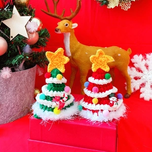 Detail of handmade knit Christmas tree hats for pets with colorful pom-poms and yellow stars