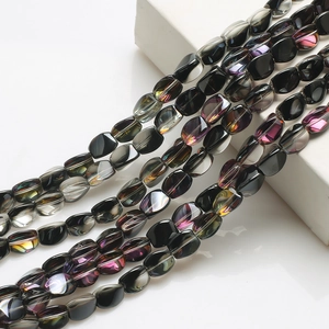 Detailed view of black faceted glass beads with rainbow luster on a white pedestal