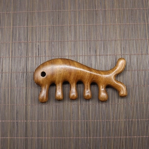 Macro shot of polished sandalwood meridian massage comb with a smooth finish and wood grain