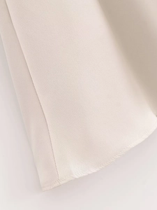 Makro-Detail von beige Satin-Kleid-Stoff mit feinen Nähten am Saum und edlem Glanz