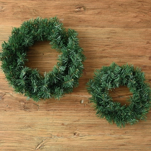 Deux tailles de couronnes de Noël en pin artificiel sur un fond en bois rustique