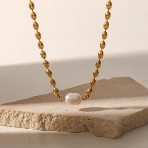 Detailed view of an oval gold bead chain necklace with a natural freshwater pearl pendant