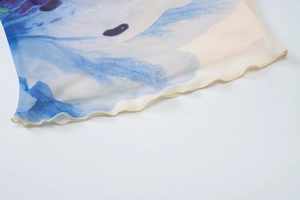Detail of blue and white mesh fabric with lettuce edge hem and abstract ink print