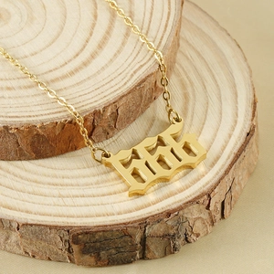 Detail of 18K gold stainless steel necklace with gothic 666 pendant on wood base