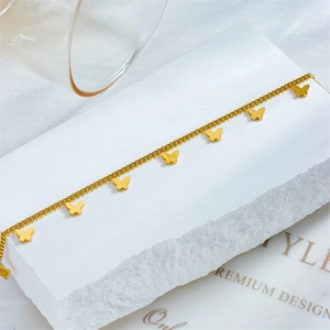 Detailed close-up of a multi-layer rose gold butterfly bracelet on a white stone base
