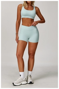 Detail of high-waist criss-cross fitness shorts and U-neck sports bra in light blue