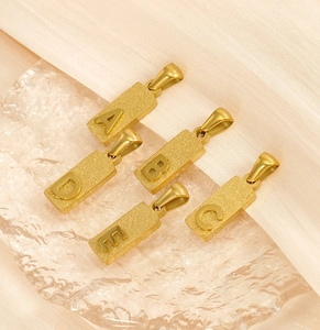 Detail of gold titanium rectangular alphabet pendants A to E on crystal ice blocks