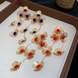 Detailed macro view of vintage hollow floral tassel earrings with blue and red gems