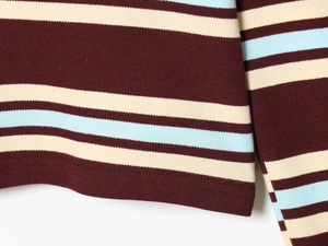 Detail of striped knit top showing hemline stitching and fabric texture on white background