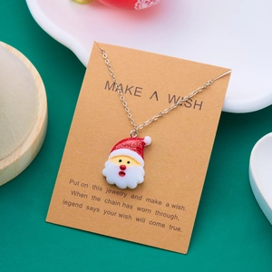Weihnachtskette mit Weihnachtsmann-Anhänger auf Wunschkarte vor grünem Hintergrund
