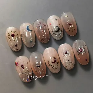 Detail of luxury frosted press-on nails with golden celestial moon and star patterns