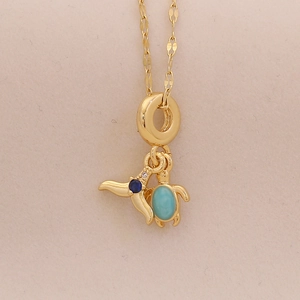 Macro detail of a golden turtle pendant with blue gemstones and turquoise accents