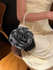 Detail of black satin camellia evening bag with elegant white pearl bead handle
