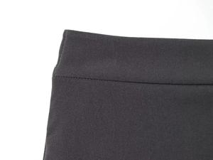 Close-up of flat waist stitching and texture on dark gray trousers with belt loops