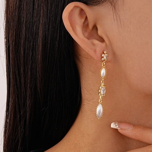 Detail of vintage gold pearl earrings with zircon tassels shown on a model