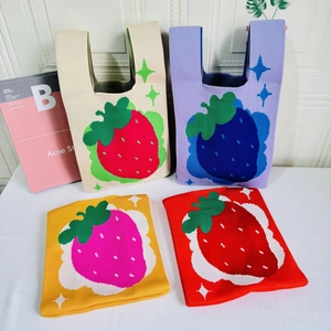 Detail of four colorful strawberry pattern knit tote bags showing texture and design