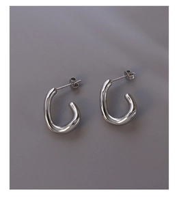 Close-up of minimalist silver C-shaped irregular oval stud earrings in polished metal