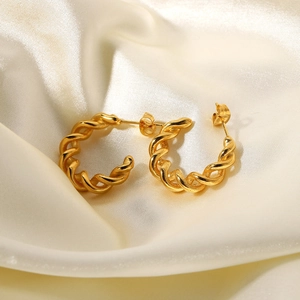 Close-up of 18K gold-plated C-shape earrings with twisted rope texture on silk fabric