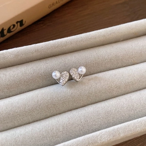 Détail macro de boucles d'oreilles cœur en argent avec cristaux pavés et perles blanches