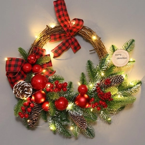 Christmas wreath with buffalo plaid bow, red berries, pine cones and LED lights on grey background