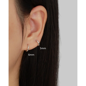 Detail view of 5mm and 6mm S925 sterling silver hoop earrings worn on the ear