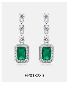 Detail shot of teardrop emerald earrings in S925 silver with a luxurious halo diamond setting