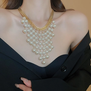 Close-up of golden fringe necklace featuring layered white pearls and chic design