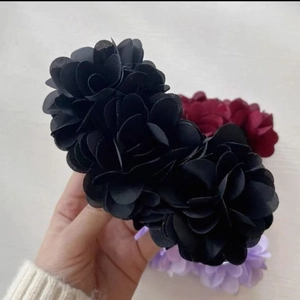 Detailed view of large fabric flower banana hair clips in red, black, and lavender tones