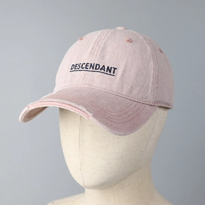 Detailed view of the vintage distressed brim and black letter embroidery on the pink cotton cap