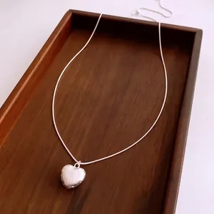 Collier à pendentif cœur brossé avec chaîne serpent fine sur plateau en bois chic