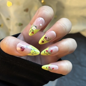 Almond fake nails with yellow French tips featuring ladybugs, berries and white pearls