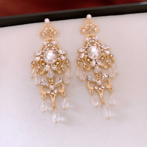 Detailed macro view of vintage gold-plated tassel earrings with crystals and faux pearls