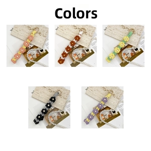 Detail view of handmade crochet daisy keychains with metal lobster clasps in 5 colors