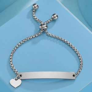 Macro shot of silver box chain bracelet with heart charm and blank curved metal bar