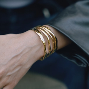 Lifestyle view of women wearing irregular golden wave cuff with glossy polished finish
