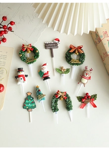 Flat lay of Christmas cake toppers featuring Santa, reindeer and trees on festive background