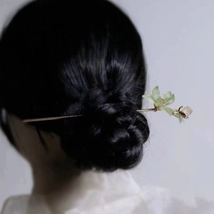 Close-up of a golden flower hair pin with light green petals on a brunette bun