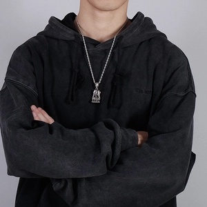 Detail of silver rope chain and ornate hollow-carved pendant on a streetwear model