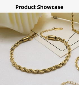 Detail of a gold braided rope chain bracelet with a lobster clasp on a white background