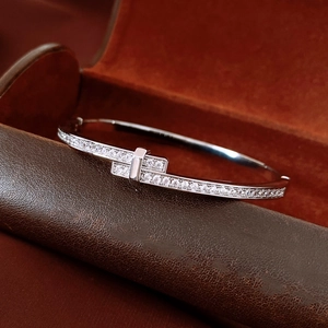 Macro shot of silver-toned double-T interlocking bangle with pavé-set sparkling crystals