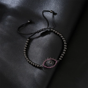 Macro view of copper evil eye pendant with micro-pave cubic zirconia on woven bracelet