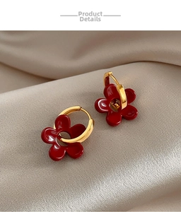 Détails de boucles d'oreilles fleurs rouges vintage avec boucles dorées sur soie
