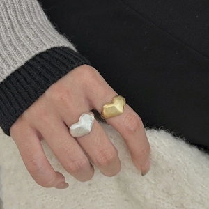 Detail of minimalist 925 silver brushed heart-shaped rings in gold and silver finish