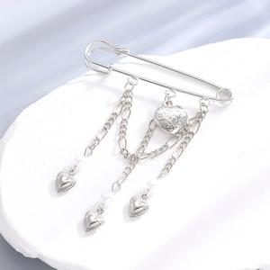 Detailed shot of silver punk chain brooch with embossed heart and pearl charms
