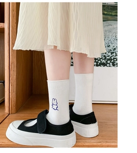 Close-up of white crew socks with blue embroidered bunny and black Mary Jane shoes