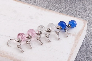 Close-up of pink, white, and blue faceted crystal sphere clip-on earrings on white wood