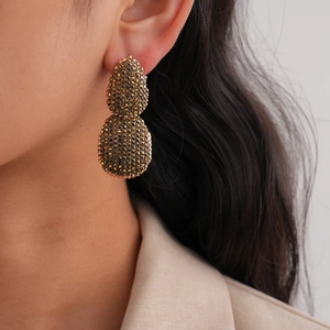 Gros plan sur boucles d'oreilles gouttes dorées à double étage portées par un mannequin