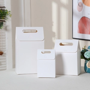 Three assorted sizes of minimalist white kraft paper gift boxes with convenient handles