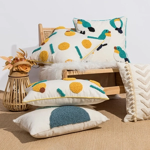 Detailed close-up of modern tufted bird and geometric patterns on linen cushion covers