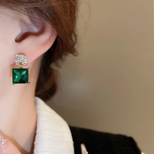 Close-up of vintage square emerald green crystal earrings with diamond accents on a model